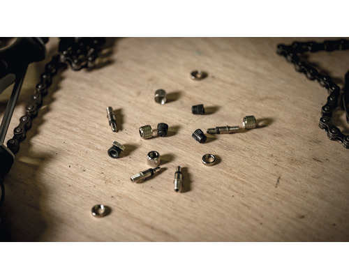 Fahrradventile und Fahrradkette auf einer Holzoberfläche