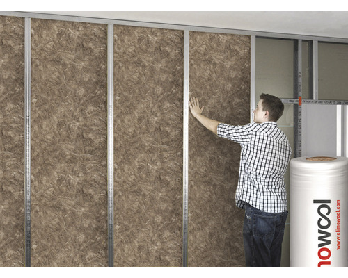 Mann befestigt Dämmwolle zwischen Metallstreben an einer Wand. Climowool Logo sichtbar.