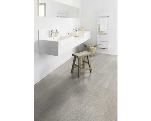 Helles Badezimmer mit Doppelwaschtisch, Heizkörper, Hocker und Bodenfliesen in Steinoptik.