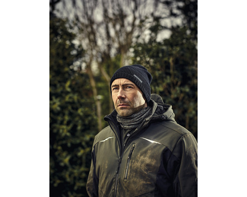 Mann mit Mütze, Schlauchschal und Arbeitsjacke im Freien