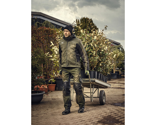 Mann in Arbeitskleidung schiebt eine Schubkarre mit Pflanzen