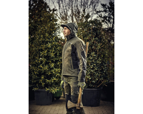 Mann in Arbeitskleidung mit Axt im Garten.