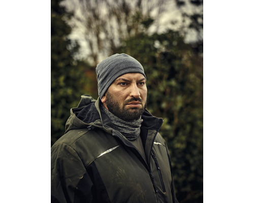 Mann mit Mütze und Arbeitsjacke im Außenbereich