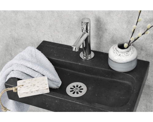 Waschbecken aus Stein mit Armatur, Handtuch, Seife und Vase