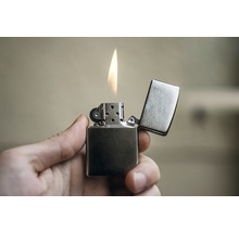 Ein Feuerzeug mit offener Flamme in der Hand