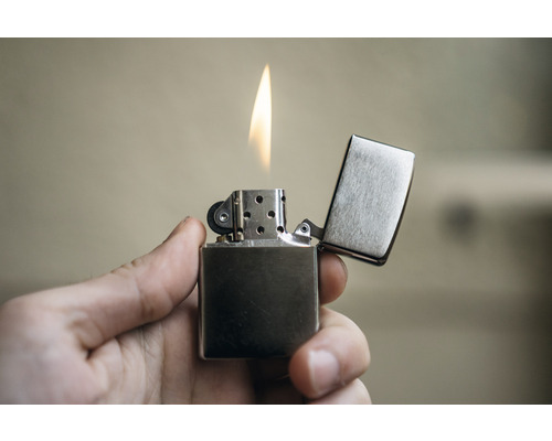 Ein Feuerzeug mit offener Flamme in der Hand