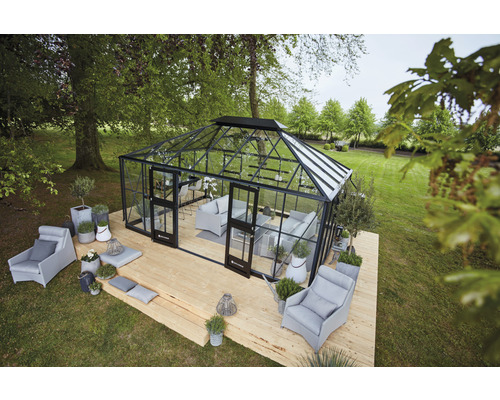 Ein Gewächshaus mit Sitzgelegenheiten auf einer Holzterrasse in einem Garten.