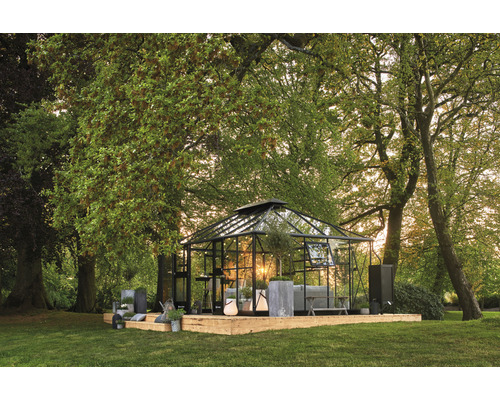 Gewächshaus auf einer Holzplattform in einem Garten mit Bäumen