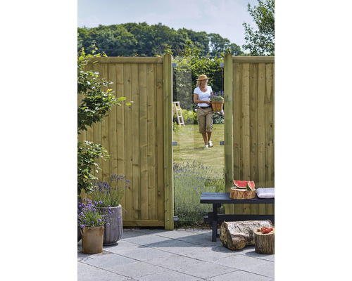 Gartenansicht mit Holzzaun, Gartentür und Frau mit Blumenkorb