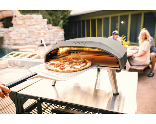 Ooni Pizzaofen mit Pizza auf Pizzaschieber im Außenbereich