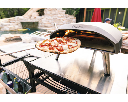 Ooni Pizzaofen mit Pizza und Zubehör im Außenbereich