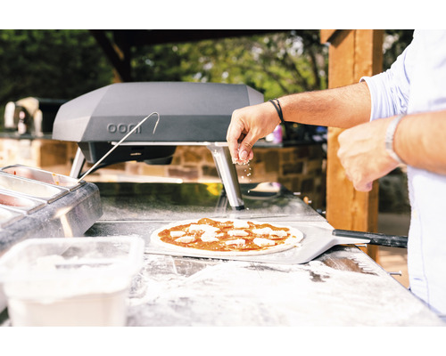 Zubereitung einer Pizza im Freien mit Pizzaofen und Zutaten
