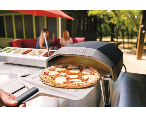 Ooni Pizzaofen mit Pizza auf Pizzaschieber im Außenbereich