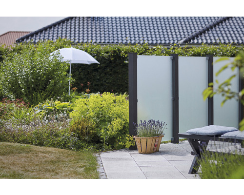 Gartenszene mit Sichtschutzzaun, Bepflanzung und Sonnenschirm