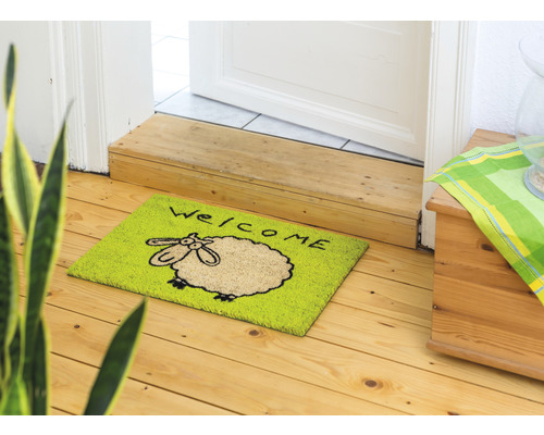Fußmatte mit Schafsmotiv und Willkommensgruß vor einer Tür