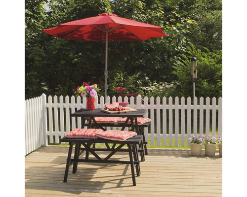 Gartenszene mit Tisch, Bänken, Sonnenschirm und Dekoration auf einer Holzterrasse vor einem Gartenzaun