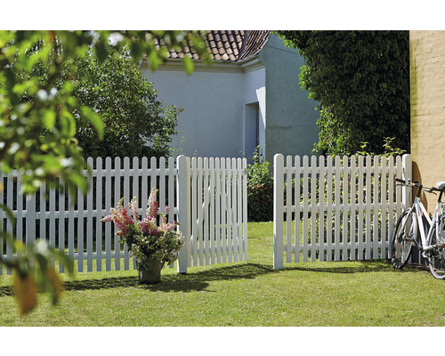 Szene mit einem weißen Lattenzaun und einem offenen Gartentor auf einer Rasenfläche