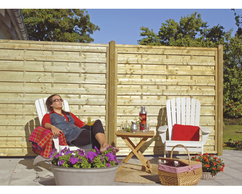 Garten mit Holzzaun und entspannter Person im Liegestuhl