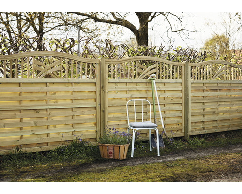 Holzzaun mit dekorativem Abschluss, Gartenstuhl und Pflanzkorb im Garten