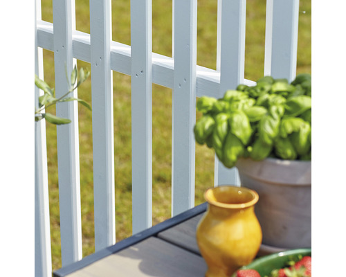 Detailaufnahme eines weißen Gartenzauns mit dekorativen Elementen auf einem Tisch