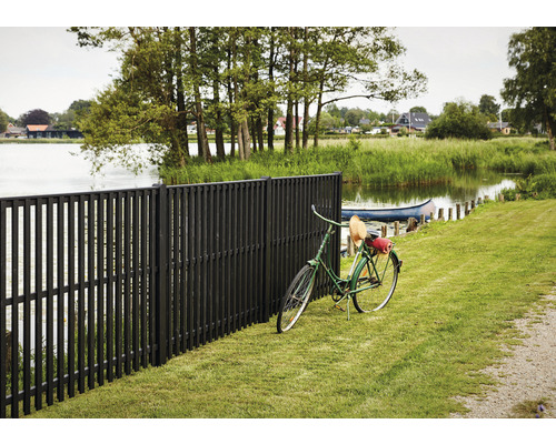 Schwarzer Holzzaun mit Fahrrad auf Rasen am See