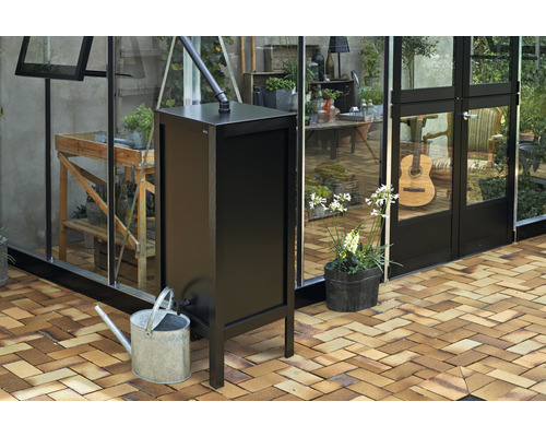 Schwarzer Regenspeicher mit Gießkanne vor Gewächshaus