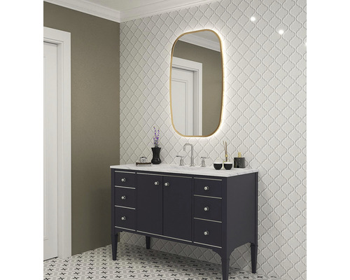 Badezimmer mit Waschtisch, Spiegel mit Beleuchtung und gemusterten Fliesen an Wand und Boden