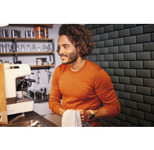 Mann in Küche mit Spüle, Kaffeemaschine und Geschirrregal