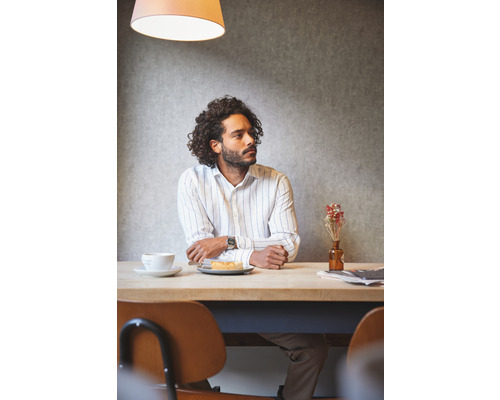 Mann sitzt an einem Tisch mit einem Getränk und einem Kuchen.