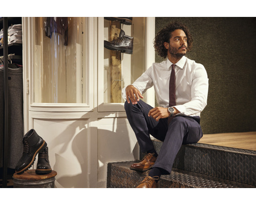 Mann in Hemd, Hose und Schuhen sitzt auf einer Treppe in einem Bekleidungsgeschäft.