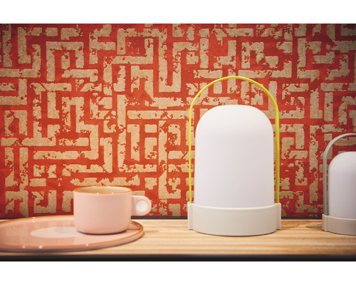 Dekorative Tischleuchte mit Griff und Muster-Tapete im Hintergrund