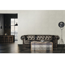 Wohnzimmer mit Ledersofa, Couchtisch und Stehlampe vor gemusterter Tapete