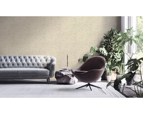 Wohnzimmer mit Sofa, Sessel und Zimmerpflanzen vor einer gemusterten Tapete.