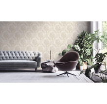Wohnzimmer mit gemusterter Tapete, Sofa, Sessel und Zimmerpflanzen.