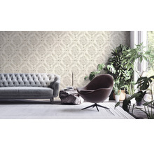 Wohnzimmer mit gemusterter Tapete, Sofa, Sessel und Zimmerpflanzen