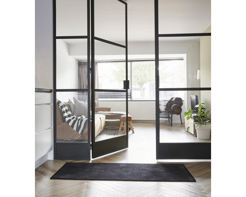 Zimmeransicht mit schwarzer Fußmatte und Glastür mit Stahlrahmen