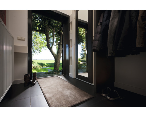 Eingangsbereich mit Fußmatte, Garderobe und Blick ins Grüne