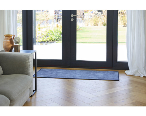 Szene mit einer Fußmatte vor einer Terrassentür, einem Sofa und einem Beistelltisch