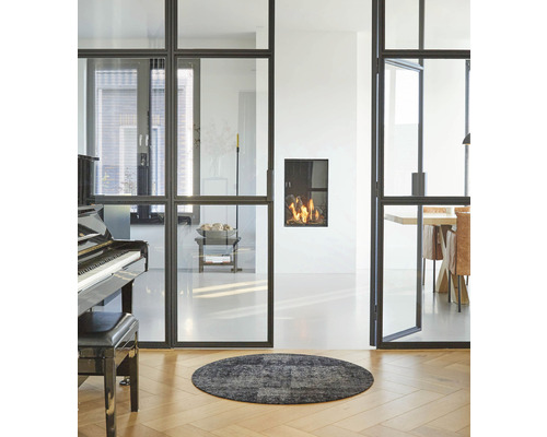 Wohnzimmer mit Glasschiebetüren, Kamin, Klavier und rundem Teppich auf Holzboden.