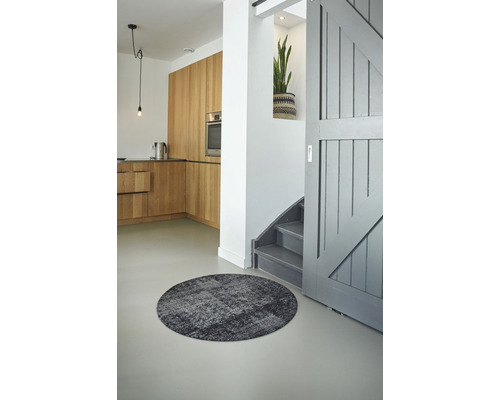 Einrichtung mit rundem Teppich, Küche und Treppe.