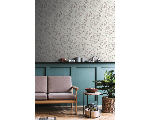 Wohnzimmer mit floral gemusterter Tapete, Sofa, Tisch und Zimmerpflanze