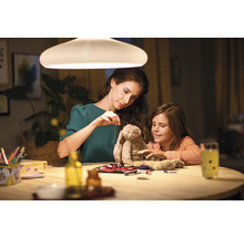 Mutter und Tochter sitzen an einem Tisch unter einer Lampe und reparieren ein Stofftier.