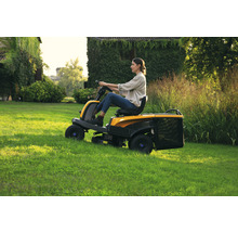 Frau fährt Rasentraktor auf Rasenfläche