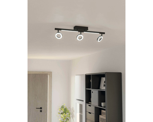 Schwarze Deckenleuchte mit drei LED-Ringen in einem hellen Raum.
