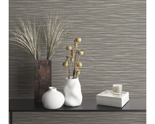 Dekoratives Arrangement mit Vasen, Pflanzen und Kerze vor einer Wandtapete