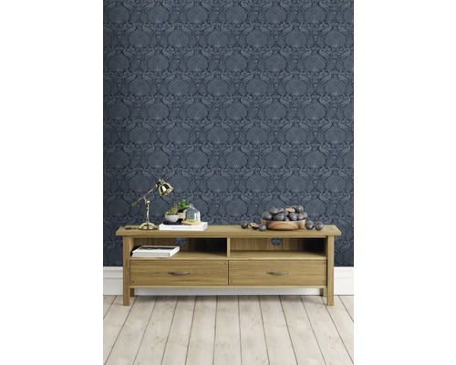 Wohnzimmer mit blau gemusterter Tapete und Holzmöbeln