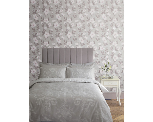 Schlafzimmer mit Bett, Nachttisch und geblümter Tapete