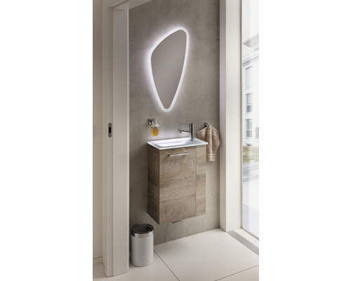 Modernes Badezimmer mit Waschtisch, beleuchtetem Spiegel und Mülleimer.