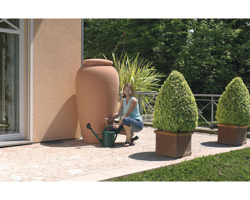 Garten mit Regenwassertank, Gießkanne und bepflanzten Blumentöpfen