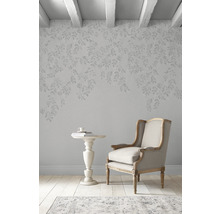 Einrichtungsszene mit Sessel, Beistelltisch und Tapete mit Blattmuster in einem hellen Raum.